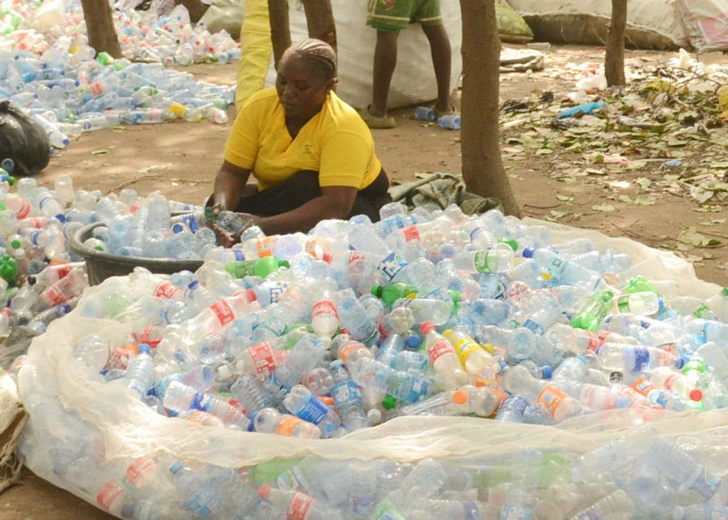 A waste picker sorting collected plastic bottles at a recovery site in Nigeria